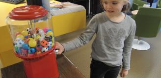 Meisje haalt speelgoed uit de speelgoedautomaat op de polikliniek KNO