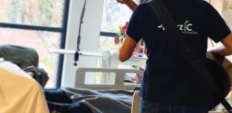 Foto van een muzikante met een gitaar, die voor een patiënt speelt