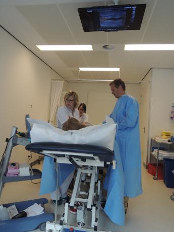 De operatiekamer met het televisiescherm waarop een patiënt het onderzoek volgt