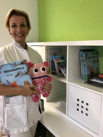 Oncologieverpleegkundige Sanna Anbeek staat blij bij de kast met boekjes