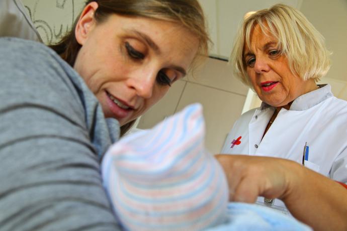Lactatiekundige geeft uitleg aan moeder over het geven van borstvoeding