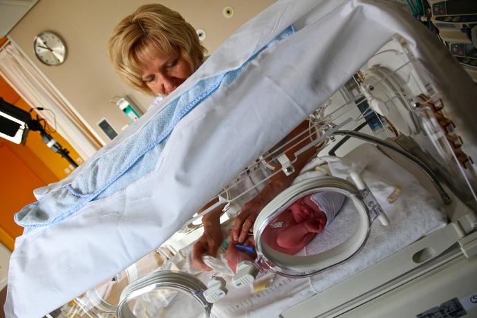 Verpleegkundige controleert baby in Couveuse