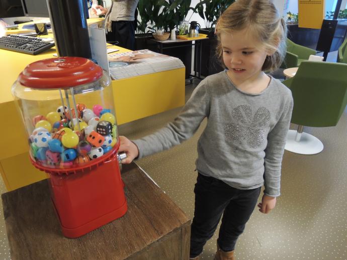 Meisje haalt speelgoed uit de speelgoedautomaat op de polikliniek KNO