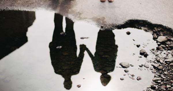 Twee mensen hand in hand weerspiegeld in plas water