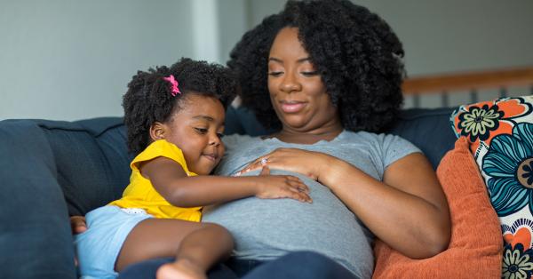 Zwangere vrouw thuis met peuter op de bank