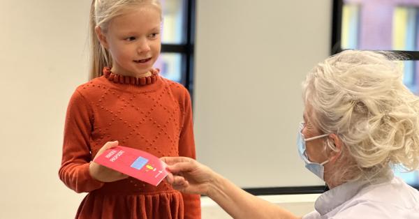 Meisje krijgt het nieuwe kinderpaspoort uitgereikt