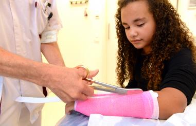 verpleegkundige knipt het gips van de arm 