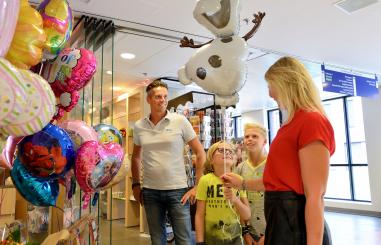 kind krijgt een ballon bij het winkeltje op de boulevard