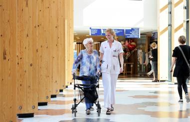 Vrouw met rollator en zorgverlener op de boulevard