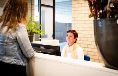 Vrouw meldt zich bij balie secretariaat van het SMC