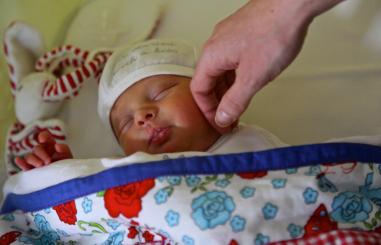 moeder strijkt met hand over wangetje kind