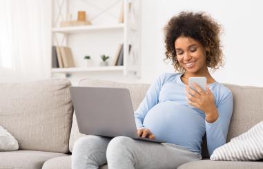 Zwangere vrouw met laptop  op de bank