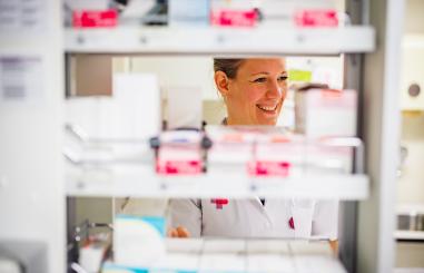 Foto van een medewerker van de apotheek bij een lade met medicijnen