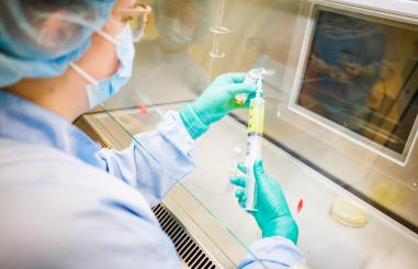 Foto van een medewerker van de apotheek die een spuit met medicatie klaarmaakt