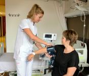 Verpleegkundige meet de bloeddruk bij een patiënt op een verpleegafdeling