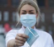 Verpleegkundige deelt mondkapje uit